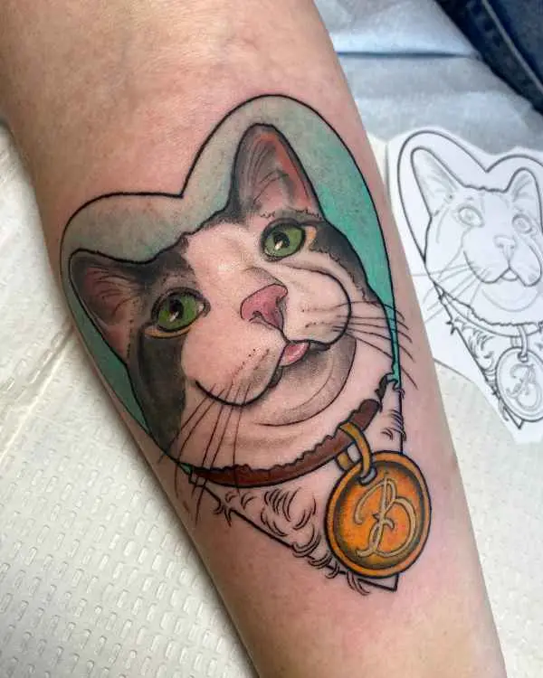 A calico cat portrait tattoo in a heart with a collar tag, by Betty Rose