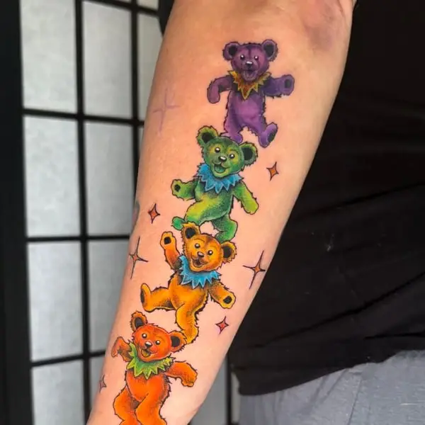 A color tattoo of four dancing bears stacked on a forearm, by Kate Elvey