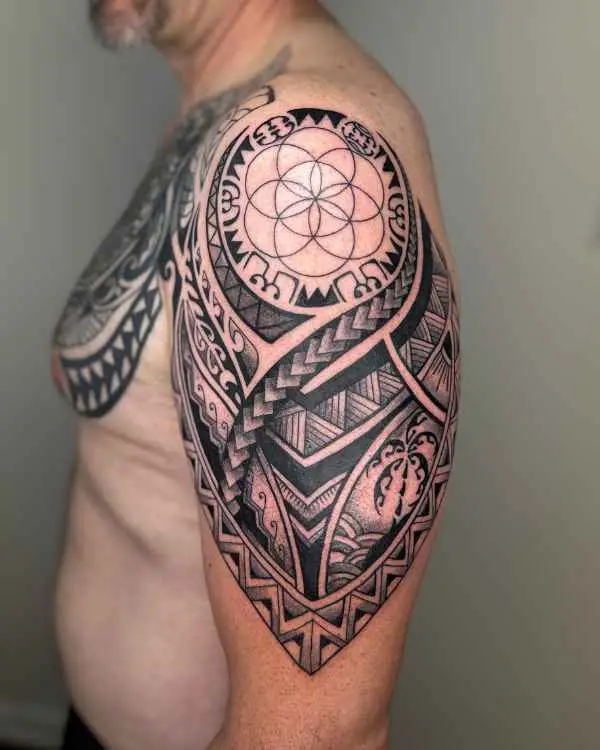 A black and grey geometric shoulder tattoo with a Seed of Life circle and tribal bands, by Jordan Joyes