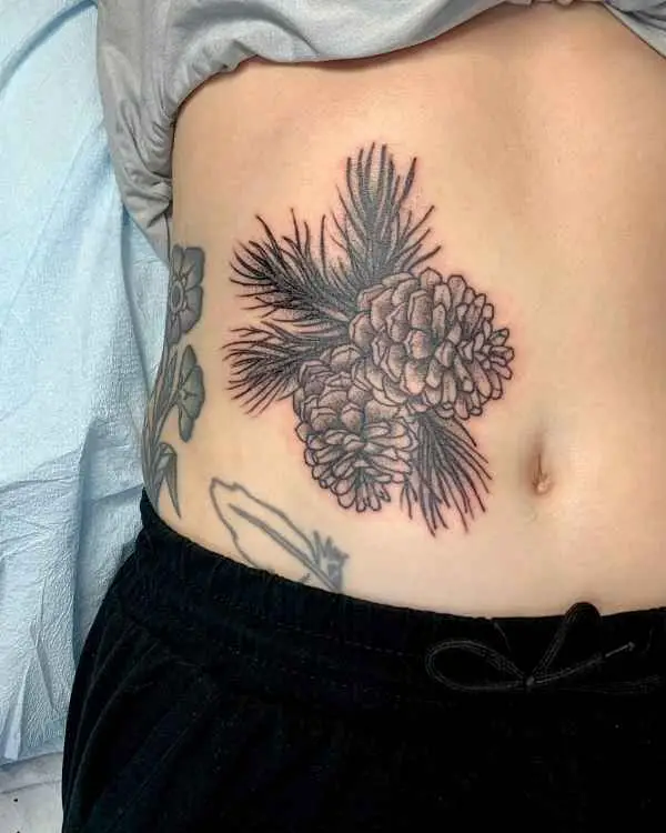 A black and grey tattoo of two pine cones and pine needles