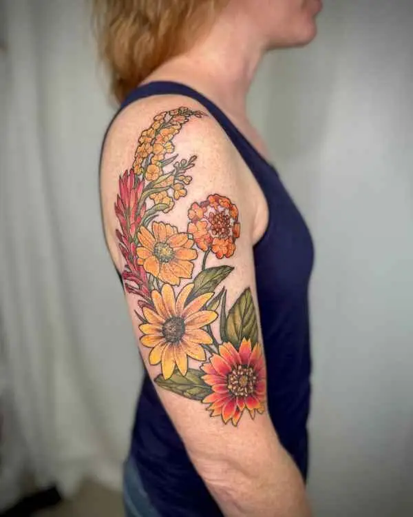 A color tattoo of sunflowers and summer wildflowers on an upper arm